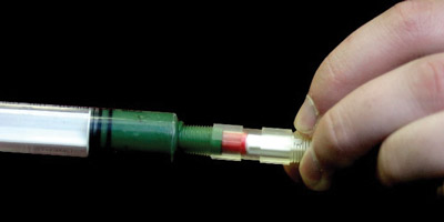 Figure 3: Filled syringe injecting grease into the Passive Grease Sampling Device Figure 3: Filled syringe injecting grease into the Passive Grease Sampling Device
